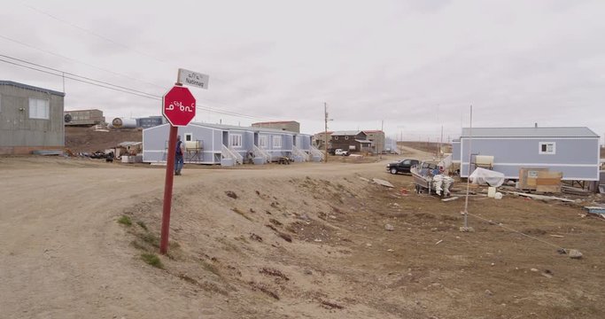 Tourist walks on road in inuit town of Pond Inlet