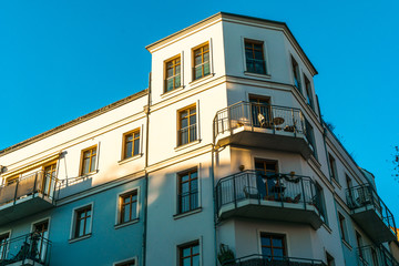 Naklejka premium white facaded corner house in warm sunlight