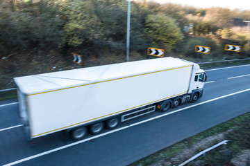 Road transport. Lorry on the road blurred in motion with focus point on the wing mirror