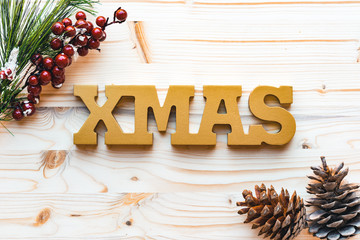Christmas decoration with fir tree branch, pine cones and word xmas on wooden background, top view, flat lay.