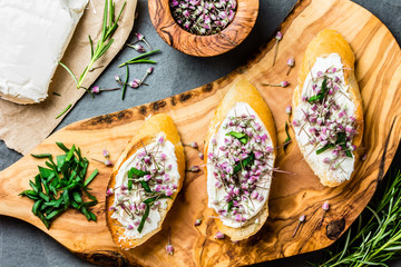 Sandwiches with cream cheese and garlic edible flowers, olive board