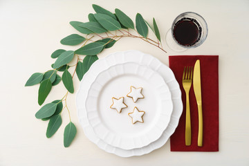 Christmas place setting with golden silverware, eucalyptus and cinnamon stars