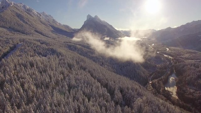 Helicopter Shot Flying Through Cloud Over Snowy Mountain Valley with Blue Sky
