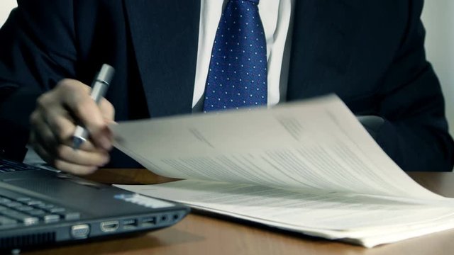 businessman at work signs documents on wooden desk