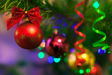 Christmas toys on Christmas tree with illumination. Bright vibrant baubles on blurred illuminated background and bokeh with soft focus. Merry Christmas and Happy New Year.
