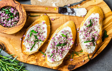Sandwiches with cream cheese and garlic edible flowers, olive board