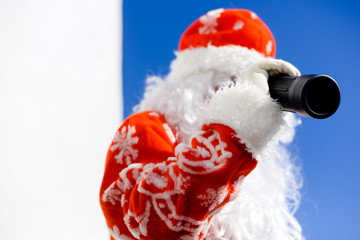 Santa Claus looking through telescope on sunny blue sky outdoors background. Closeup back side view image