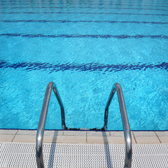 Open air swimming pool detail, steel ladder and clean turquoise water