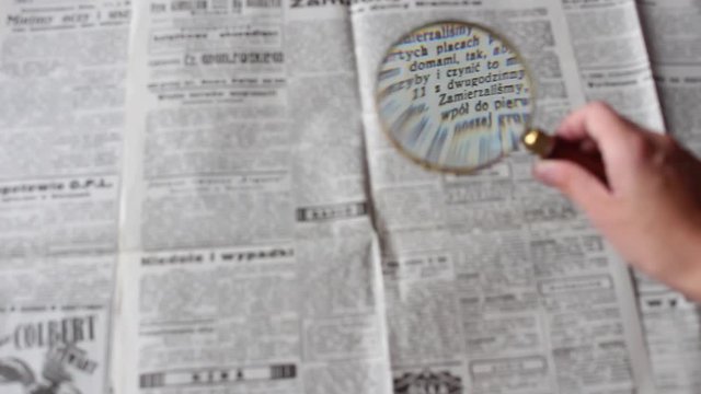 reading the newspaper through a magnifying glass