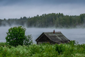 The traditional Russian log hut in poor condition on the river bank
