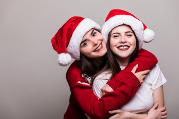 Portrait of to woman in Santa hat isolated on grey background