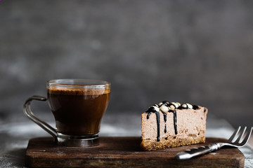 Slice of raw chocolate mousse cake with cashew, hazelnuts and dark chocolate glaze topping and...