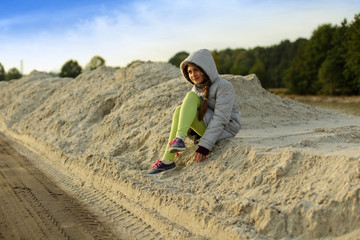 Dziewczynka siedzi na piachu. - obrazy, fototapety, plakaty
