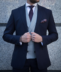 Male model in a dark navy suit with stripes posing up close