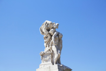 Woman kisses man statue in front of Altar of the Fatherland in Rome. Grand marble, classical temple honoring Italy's first king & First World War soldiers.