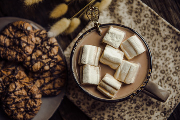 Cup of hot cocoa with marshmallow on cutting board