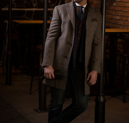 Male model with torso jacket, scarf, coat and gloves posing in a bar