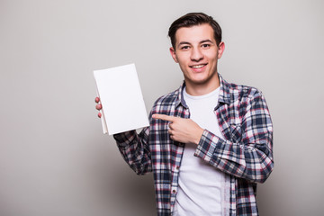 Happy cheerful young man in suit holding book and showing thumb up over white background