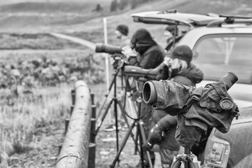 Black and white photo of a telescope used by wildlife watchers on a rainy day, selective focus.