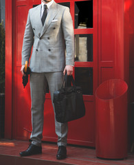 Male model in front of a red door with umbrella and  man bag