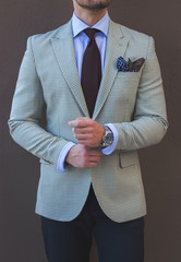 Male model in a suit posing in front of a grey wall