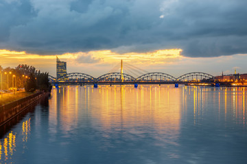 Naklejka premium Night view on the illuminated bridge with reflection on the water in Riga, Latvia. Wide angle view with copy space