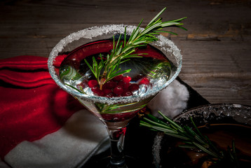 Christmas refreshing alcoholic drink with cranberries and rosemary on wooden background, with gift and decorations