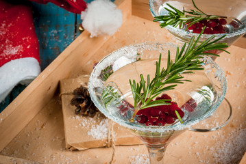 Christmas refreshing alcoholic drink with cranberries and rosemary on wooden background, with gift and decorations