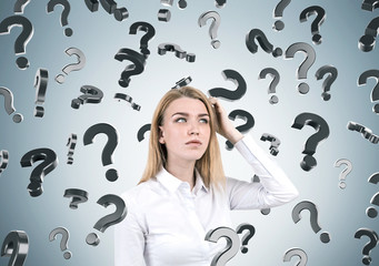 Blond woman and question marks on gray wall