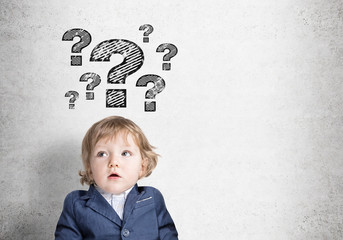 Baby boy and question marks on concrete wall