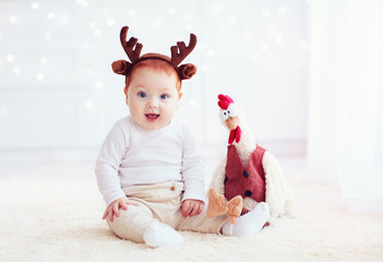 cute baby reindeer and his fellow rooster cock toy on christmas background