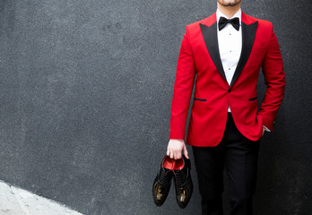 Malemodel in a suit posing with shoes in his hands