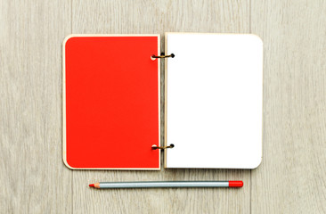 Opened blank notepad with colorful pencils on wooden table