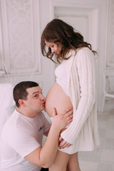 Family waiting for baby's birth. A pregnant woman and her husband wearing white clothing