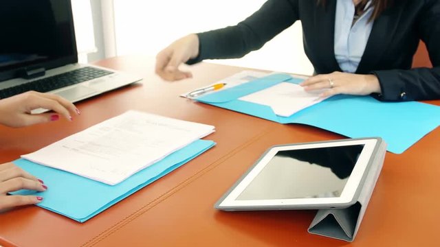 documents sign: two businesswomen at work in office