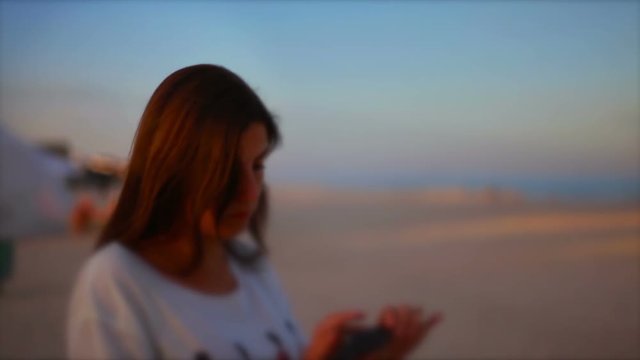 young woman uses a smartphone in the evening on the beach hd