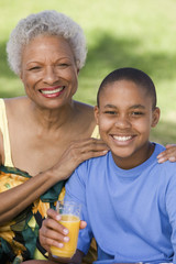 Portrait of a boy holding glass of orange juice with grandmother 