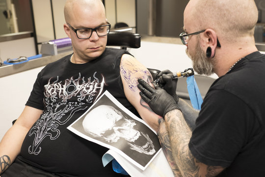 Sweden, Tattoo artist working on arm tattoo