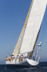 Group of crew members sitting on the side of a sailboat in the ocean