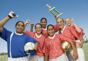 Group portrait of excited female soccer players holding winning trophy © MDBPIXS