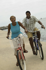 Obraz premium Portrait of a happy African American couple cycling on the beach
