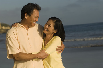 Happy couple embracing on beach while looking at each other