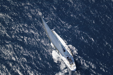 Top view of a sailboat in the peaceful blue ocean