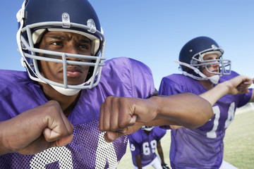 Determined young football players looking away while playing on field