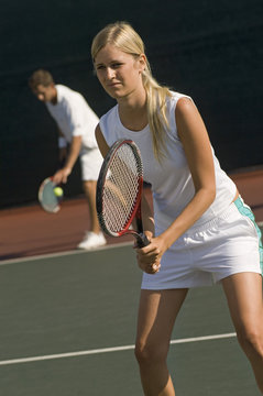 Man and woman playing doubles at the tennis court