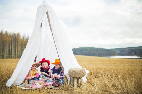 Finland, Central Finland, Aanekoski, Children (8-9) wearing cowboy hats sitting in tent