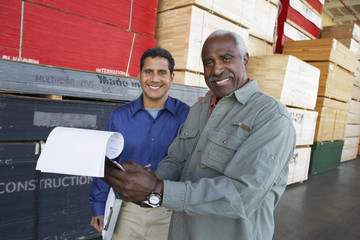 Portrait of happy warehouse workers holding clipboards