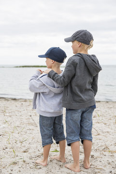 Sweden, Gotland, Boys (6-7, 8-9) in baseball caps standing at beach