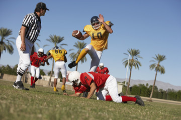 Rugby player trying to block rivalry team member while referee watching on field