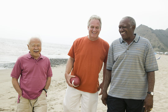 Three senior men walking on beach